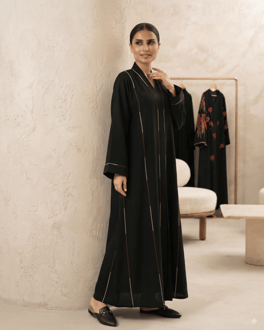 Model wearing Arooba designer black abaya with gold vertical stripe detailing.