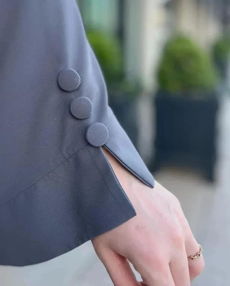 Close-up of Ayzee gray abaya sleeve featuring decorative fabric buttons and slit detail.