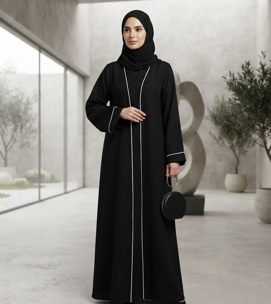 Woman wearing a black Sayarra abaya with white trim and matching hijab.