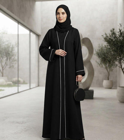 Woman wearing a black Sayarra abaya with white trim and matching hijab.