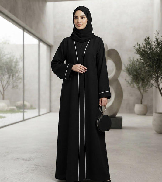 Woman wearing a black Sayarra abaya with white trim and matching hijab.